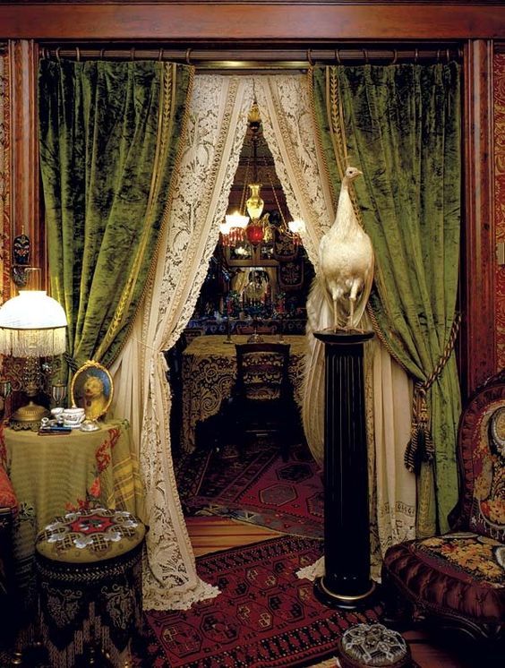 an ornately decorated room with green drapes and white curtains on the windowsill