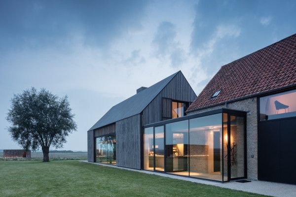 the house is made out of wood and has glass walls on both sides, while it's surrounded by grass