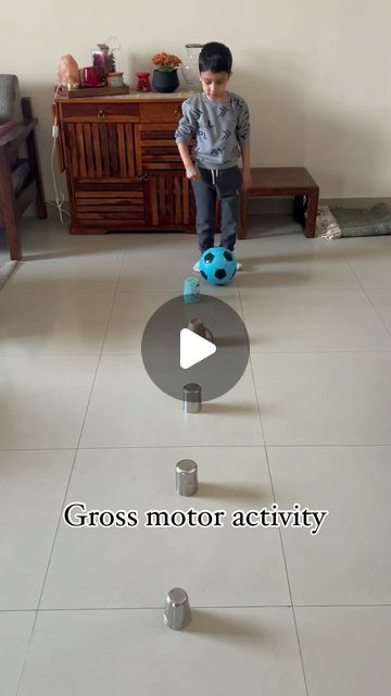 a young boy playing with a blue ball on top of a toy scooter