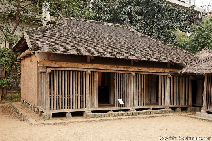 an old wooden building with thatched roof and bamboo shutters on the outside, surrounded by trees