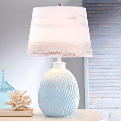 a lamp that is sitting on top of a table next to a vase and other items