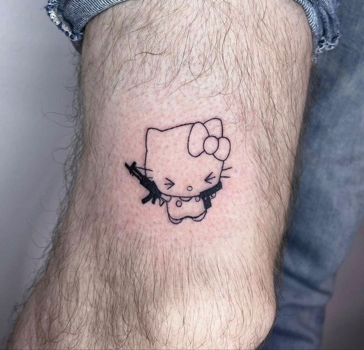 a hello kitty tattoo on the left ankle is shown in black and grey ink with an arrow