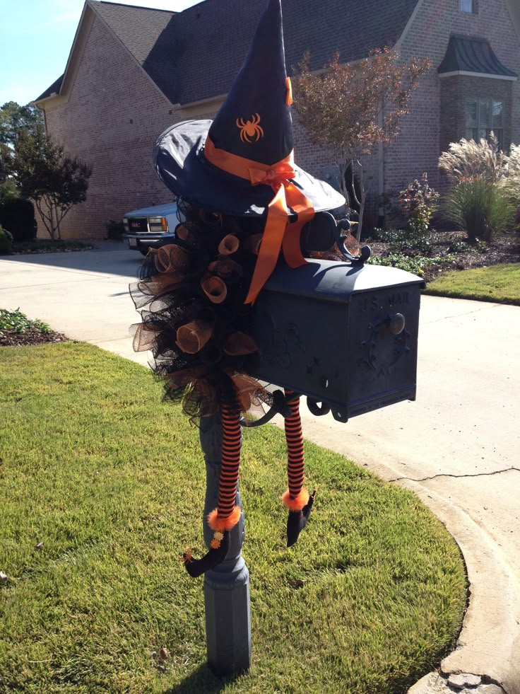 a mailbox with a witch hat and orange striped socks on it's head