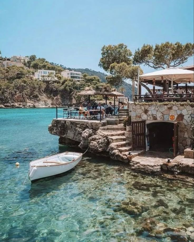 there is a boat that is in the water near some buildings and people sitting at tables