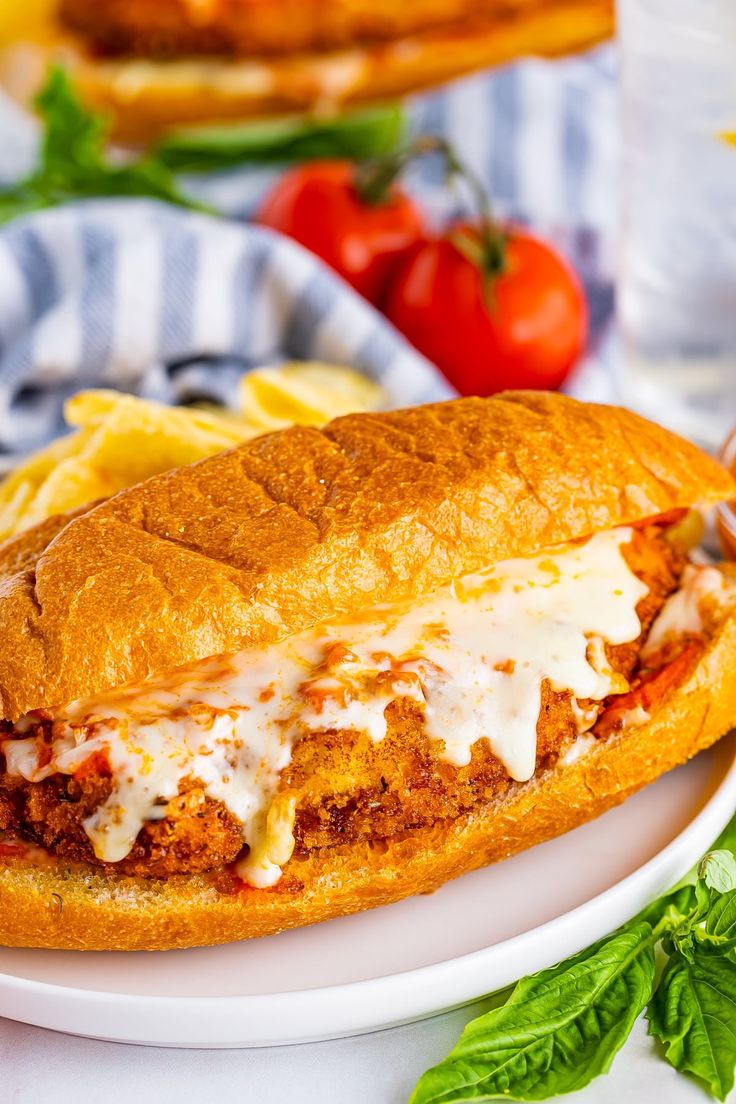 a sandwich with meat, cheese and sauce on a plate next to some pasta chips