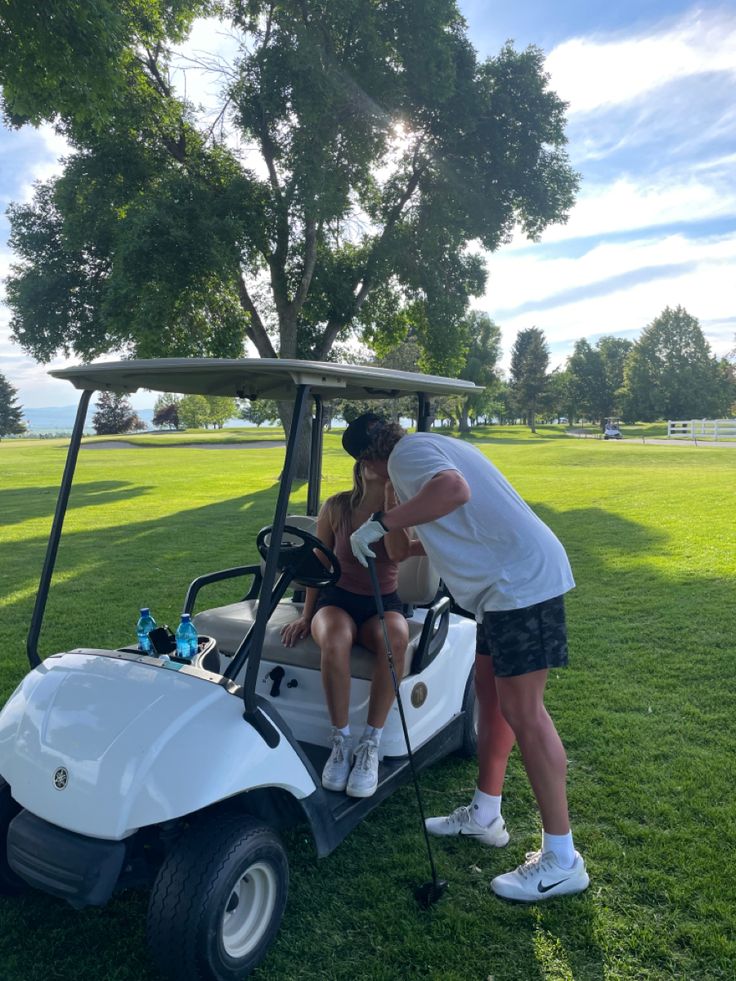 a man and woman are sitting on a golf cart