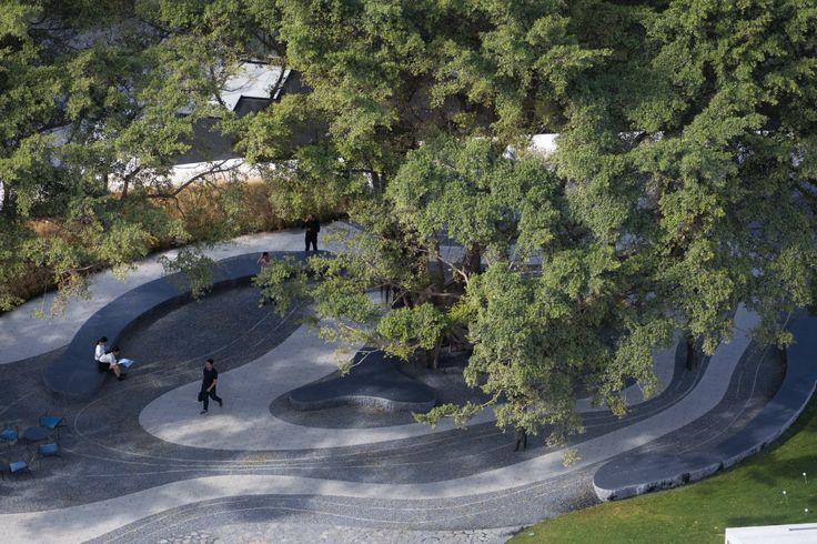 an aerial view of people walking around a skateboard park with ramps and trees in the background