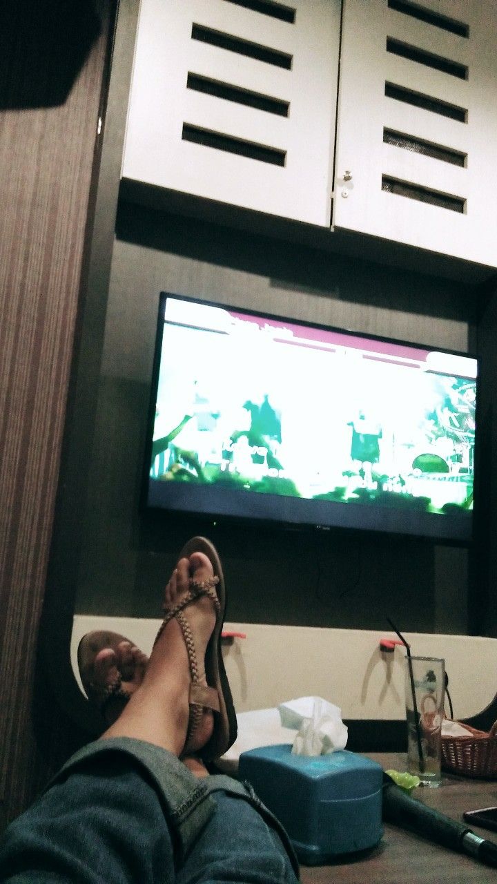 a person with their feet up in front of a flat screen tv