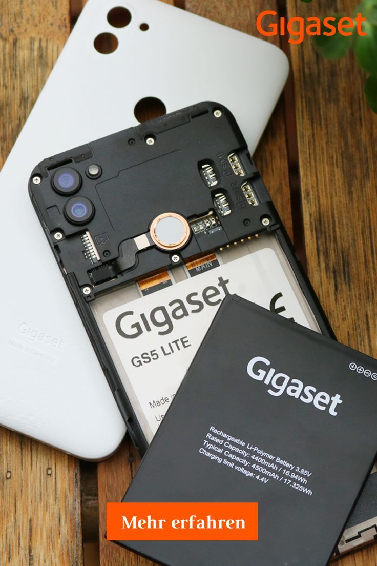 an open cell phone sitting on top of a wooden table next to a battery cover