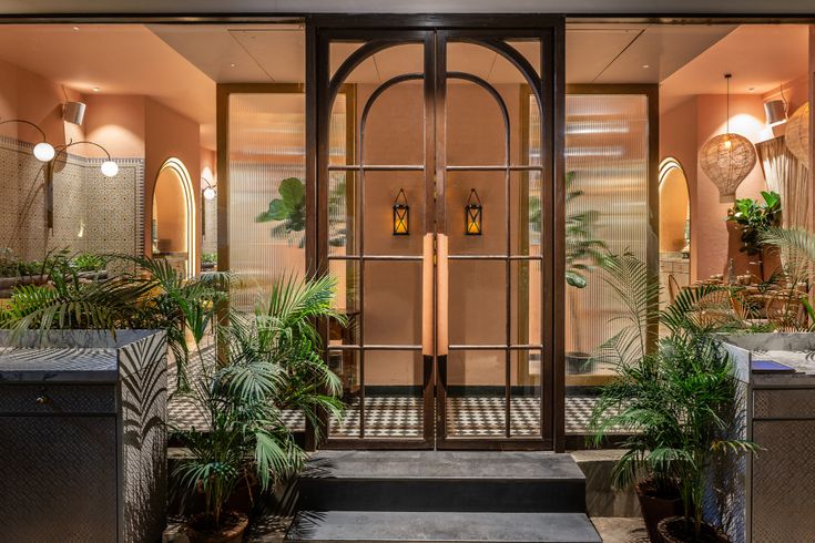 an entrance to a building with potted plants and lights on the side walk way