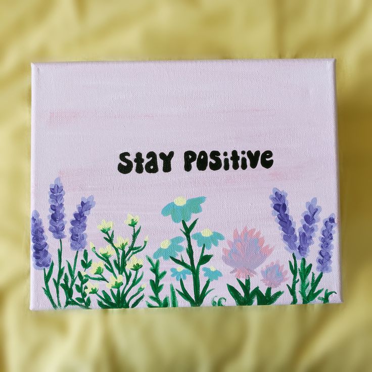 a painting with the words stay positive painted on it and flowers in the foreground