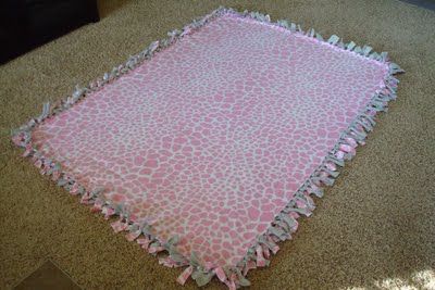 a pink and white blanket laying on the floor