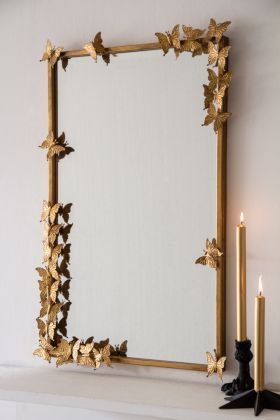 a mirror sitting on top of a mantle next to a lit candle and some candles