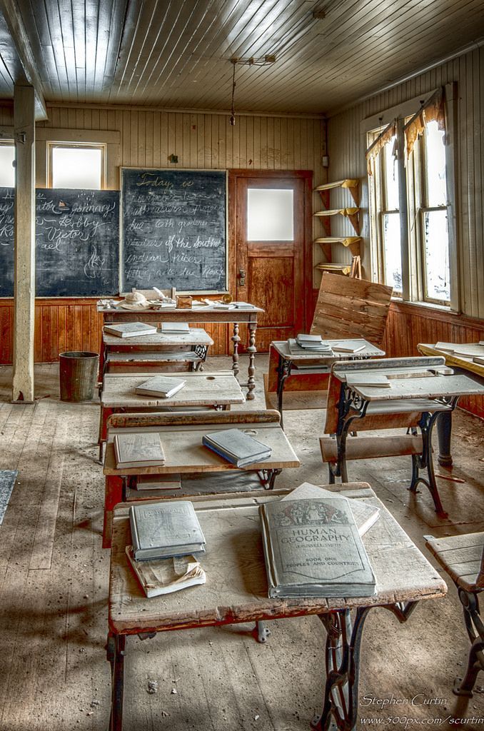 an old classroom with wooden desks and chalkboard