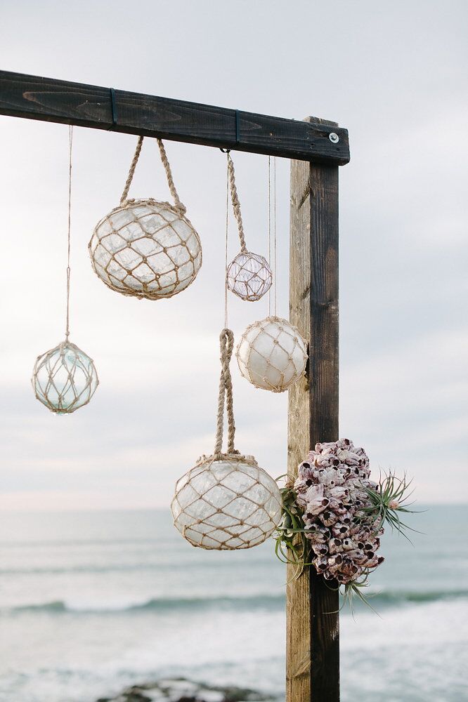 some white balls hanging from the side of a wooden structure near the ocean with flowers