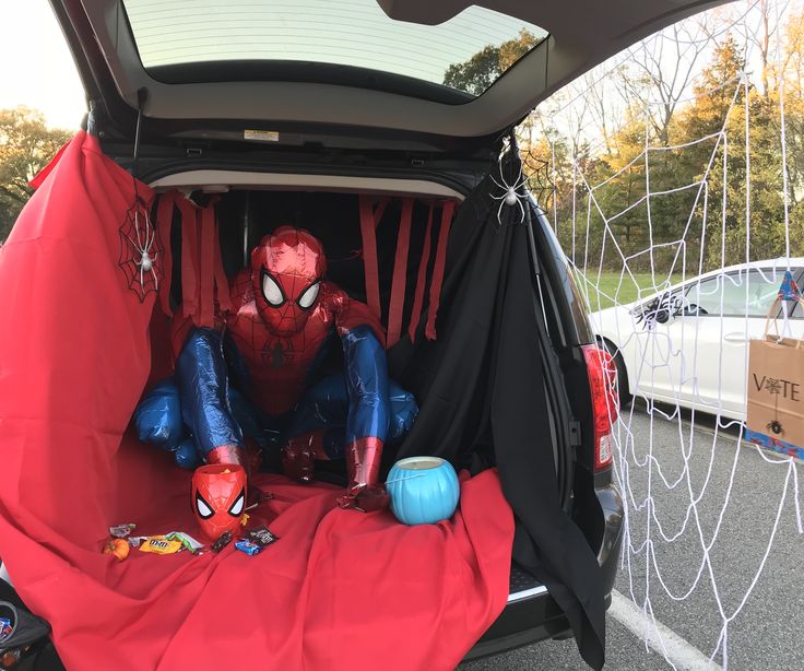 a spider man sitting in the back of a car with its trunk open and toys inside