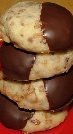 three chocolate covered cookies stacked on top of each other in front of an orange plate