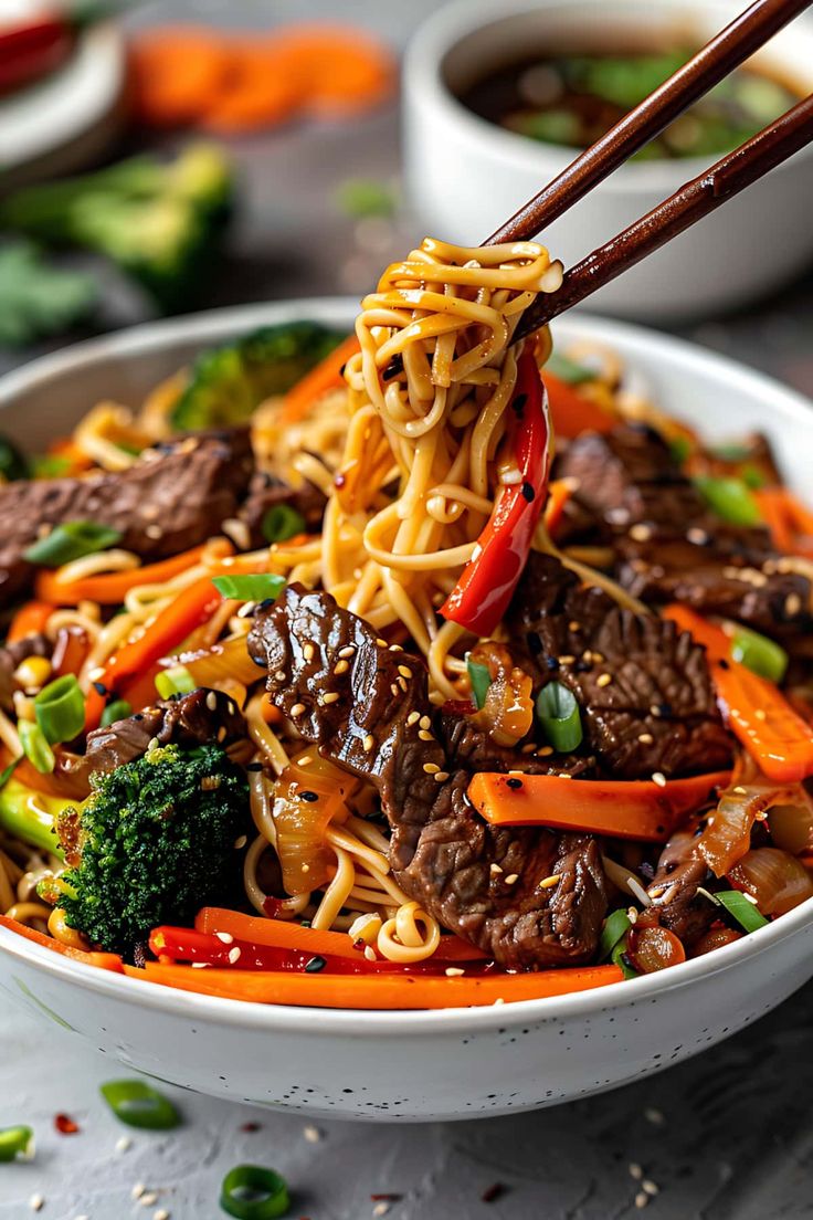 a white bowl filled with beef and veggies being held by chopsticks