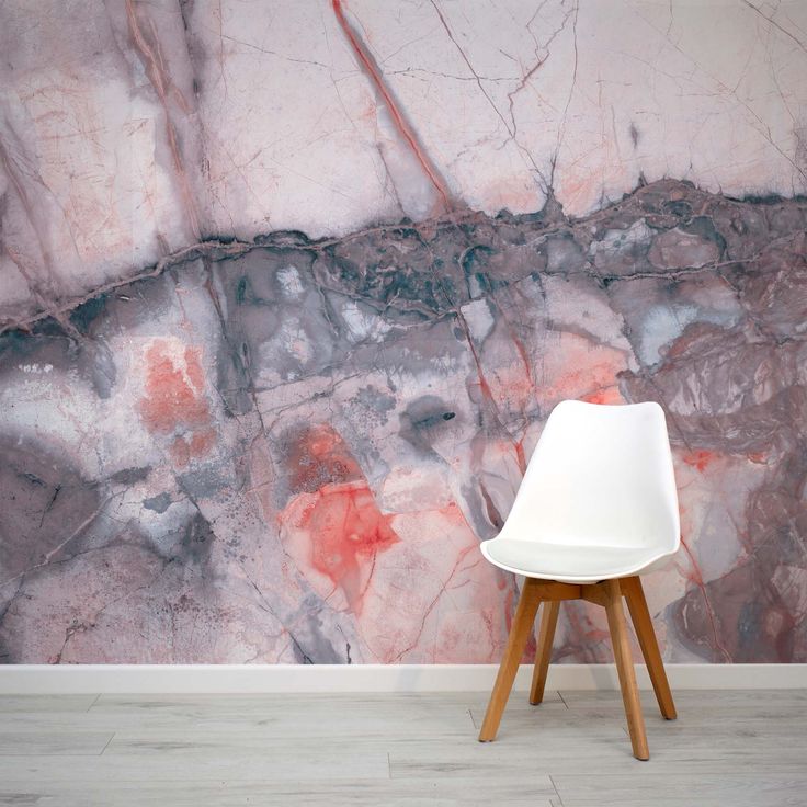 a white chair sitting in front of a wall with red and grey paint on it