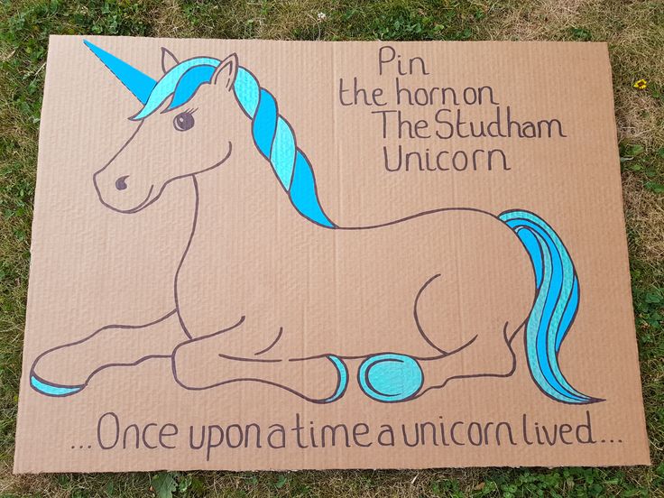 a cardboard sign with an image of a unicorn sitting on the ground in front of it