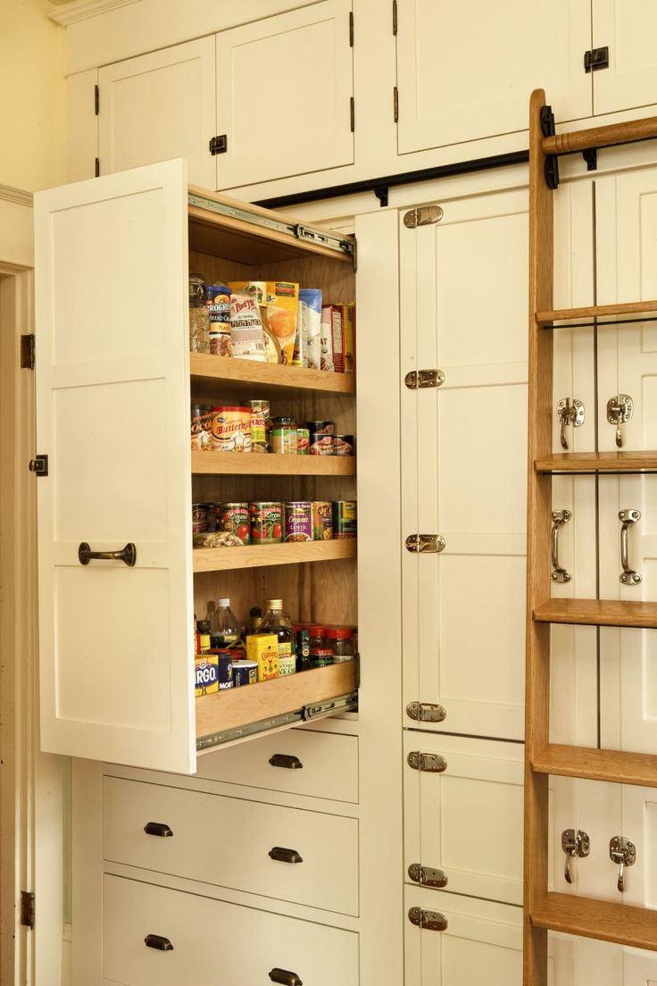 an open cabinet in a kitchen filled with lots of drawers and cupboards next to a ladder