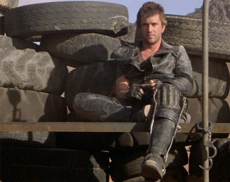 a man sitting in the back of a truck with his foot on the ground next to tires