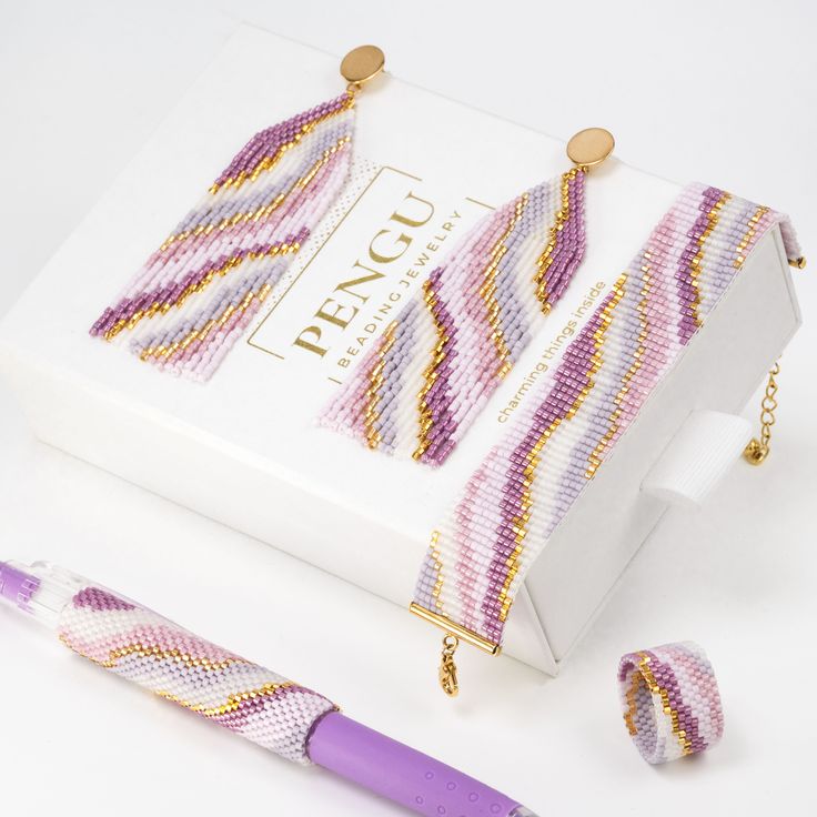 a purple pen sitting next to a white box and some beads on the inside of it