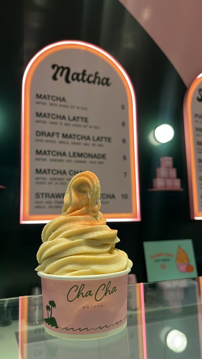 an ice cream sundae sits on a table in front of two menus for matcha