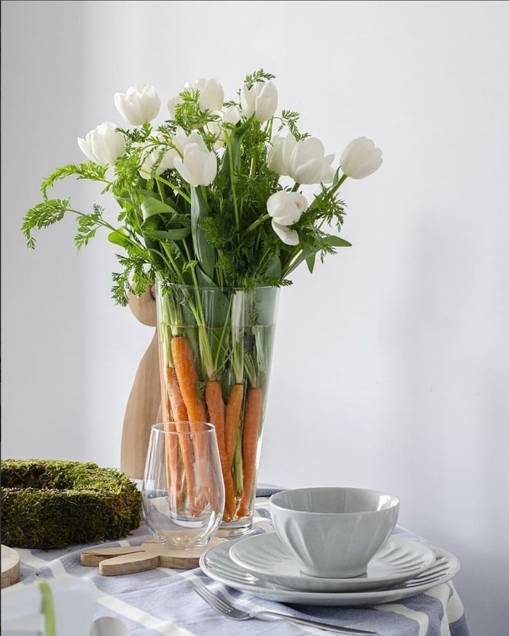 a vase filled with white flowers sitting on top of a table next to a plate