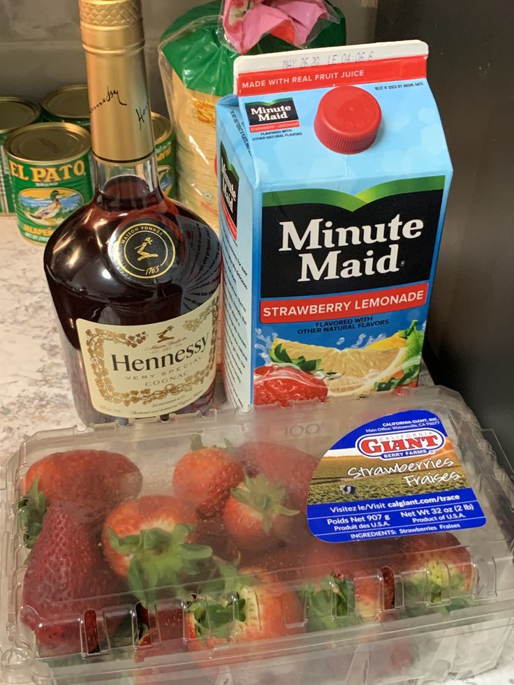 some strawberries are in a plastic container next to a carton of marmalade