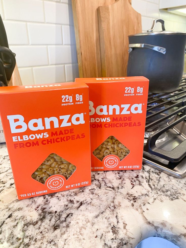 two boxes of bananas sitting on top of a counter next to a pan and stove