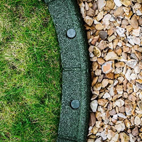 a green bench sitting on top of a lush green field next to rocks and grass