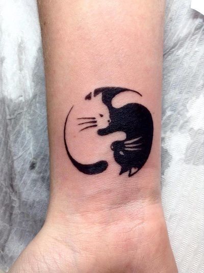 a black and white cat tattoo on the wrist