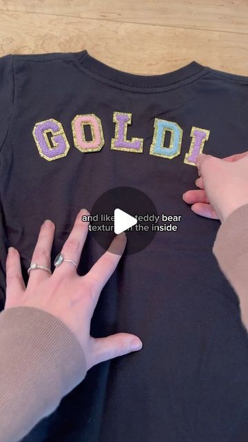 two hands are holding onto a t - shirt with the word goldi on it