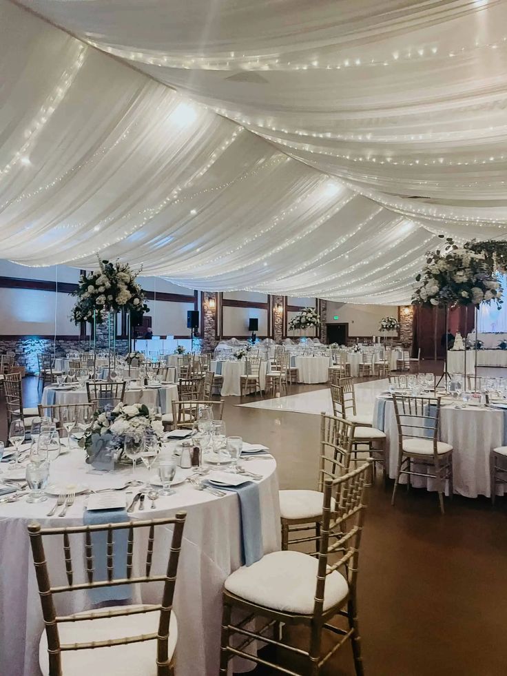 a banquet hall with tables and chairs covered in white draping