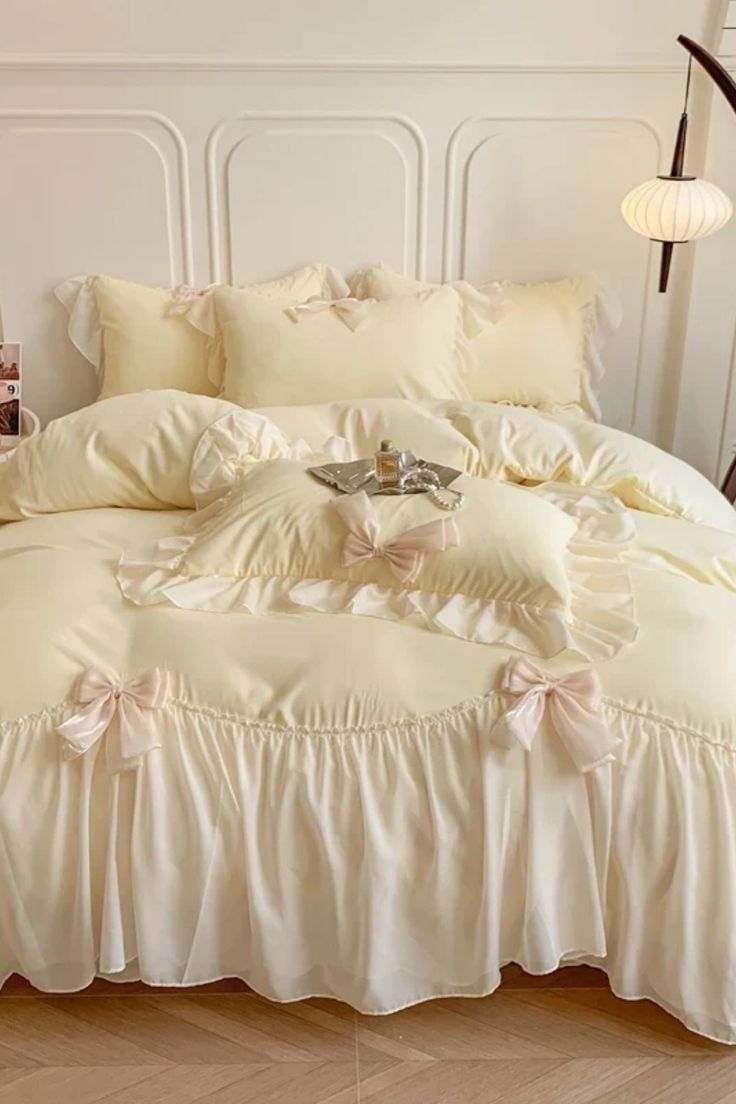 a white bed with ruffled sheets and pillows