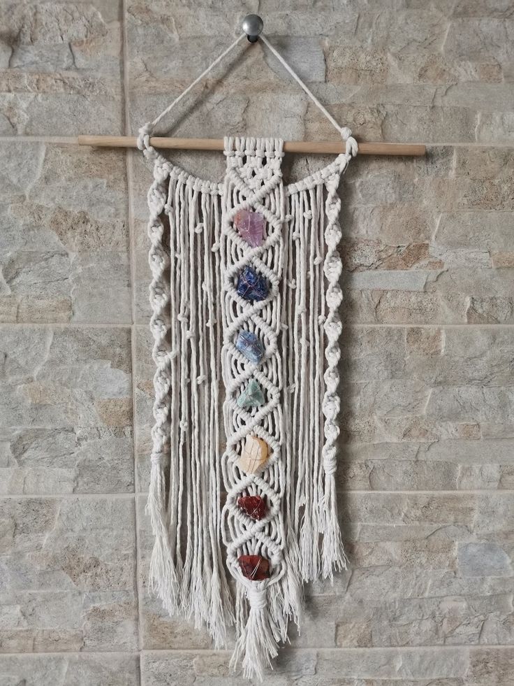 a macrame hanging on a brick wall with beads and stones in it's center