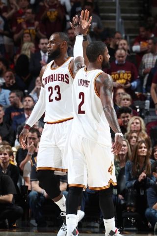 two basketball players high fiving each other in front of an audience at a game