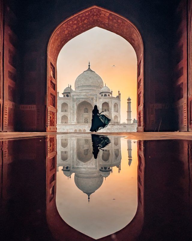 a person standing in front of a building with a reflection on the water