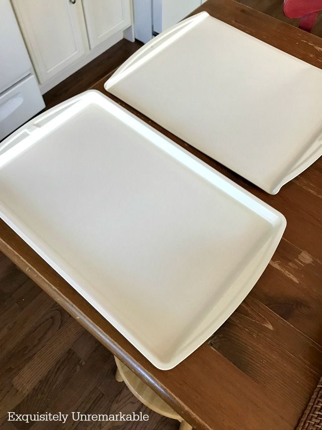 two white trays sitting on top of a wooden kitchen counter next to each other