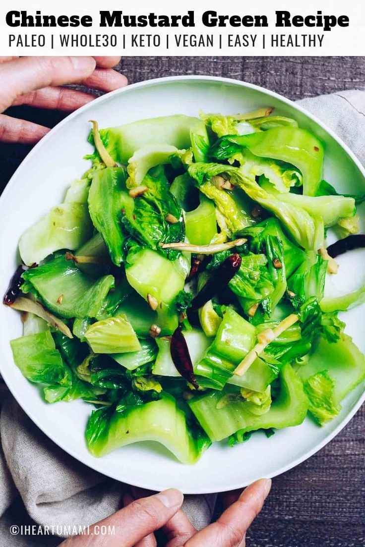 a white plate topped with green vegetables on top of a wooden table next to a napkin