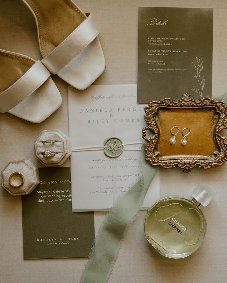 the wedding stationery is laid out with shoes, rings, and jewelry