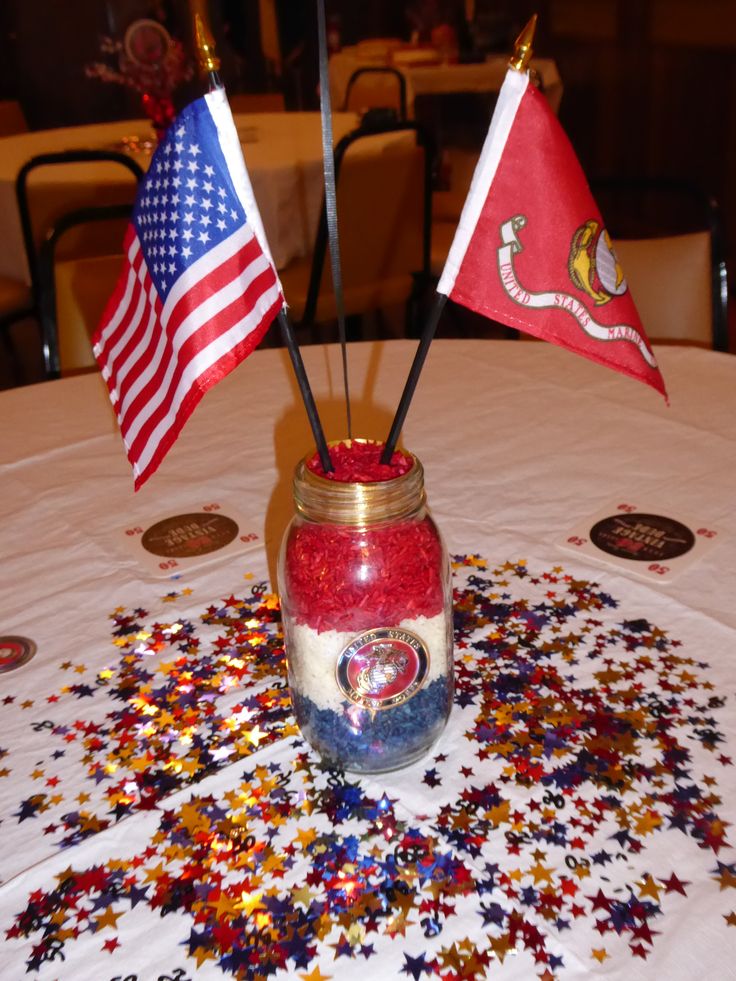 two flags are placed in a jar on a table with confetti scattered around it