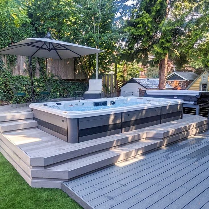 a hot tub sitting on top of a wooden deck next to a lush green field