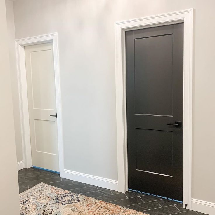 an empty room with two doors and a rug on the floor