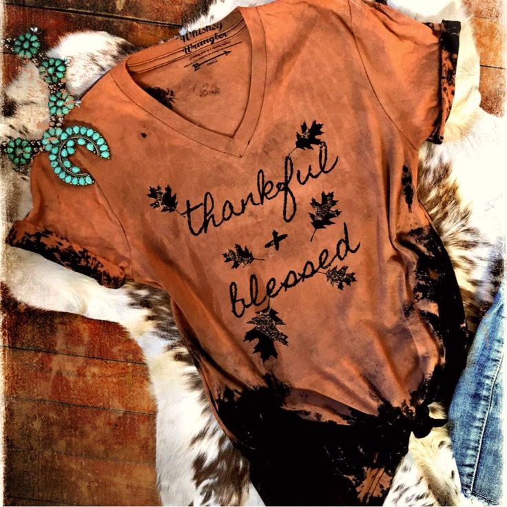 Thankful And Blessed Graphic T-Shirt Our Thankful + Blessed V-Neck Tee Fades From Rust Colors To Black And Features Falling Leaves! All Whiskey Wrangler Tees Are First Dyed By Hand So No Two Are The Same. Pair With Your Favorite Denim. **These Are Hand Bleached! Each Tee Is A Little Different With Bleach Patterns. Custom Bleach Splatter Spots By Whiskey Wrangler. Printed On A Unisex Bella Canvas Tri-Blend Crew Neck Tee. Halloween Fall Autumn Thanksgiving V-neck Letter Print T-shirt For Fall, Fall V-neck T-shirt With Letter Print, Fall Letter Print V-neck T-shirt, Distressed Tie Dye T-shirt For Fall, Distressed Tie-dye T-shirt For Fall, Distressed Tee, Thankful And Blessed, Winter Design, Falling Leaves