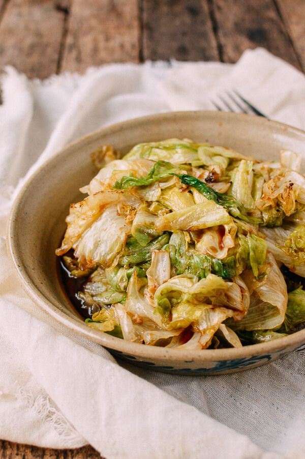 a bowl filled with cabbage and other vegetables on top of a table next to a fork