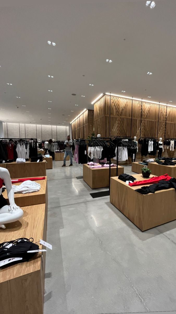 the inside of a clothing store with clothes on display and other items in wooden boxes