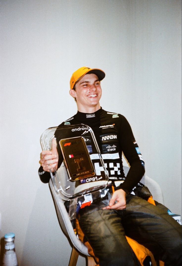 a man sitting in a chair with a cell phone on his lap and smiling at the camera