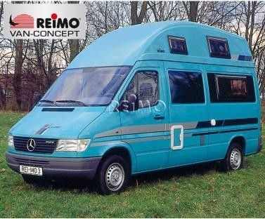 a blue van parked on top of a lush green field